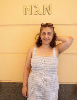 Dimitra står med förkläde på och tittar in i kameran på Lesbos i Grekland.