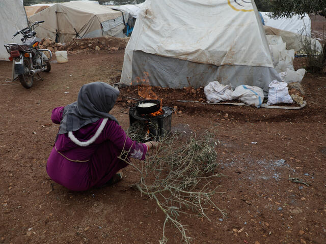 En syrisk kvinna använder grenar från ett olivträd som ved för att laga mat