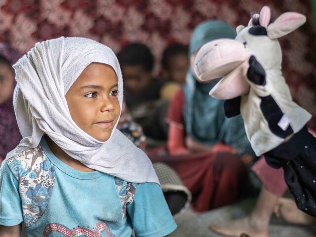 Ein Kind schaut auf eine Handpuppe in Form einer Kuh in Jemen