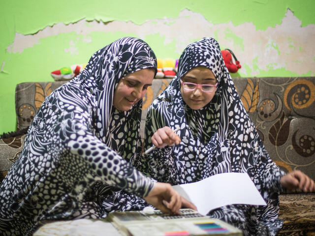 Mamma och dotter läser läxor tillsammans i Syrien