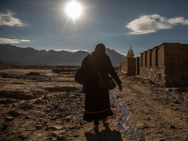 En äldre kvinna går från hem till hem i Afghanistan