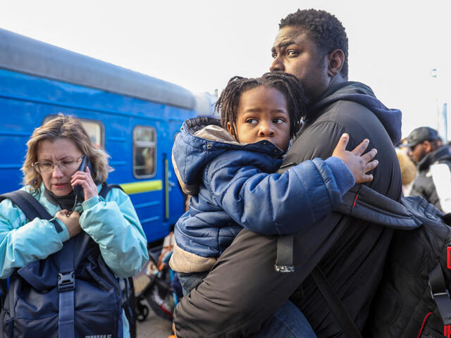 En pappa håller om sitt barn i väntan på ett evakueringståg från Kiev, Ukraina.
