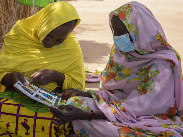Fantaou Mallam Kiari, 20, och en annan kvinna i Diffa i Niger läser en RESCUE-broschyr som visar hur man kan förebygga undernäring hos barn. Mödrar som Fantaou får kontantstöd och affärsutbildning från RESCUE för att hjälpa dem att försörja sina familjer.