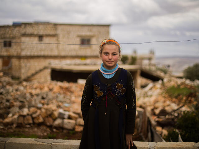 Krig och jordbävning i Syrien: Liten flicka står framför sitt förstörda hem i nordvästra Syrien.