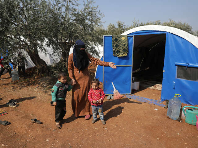 Kvinna och hennes barn framför deras tält i Syrien.