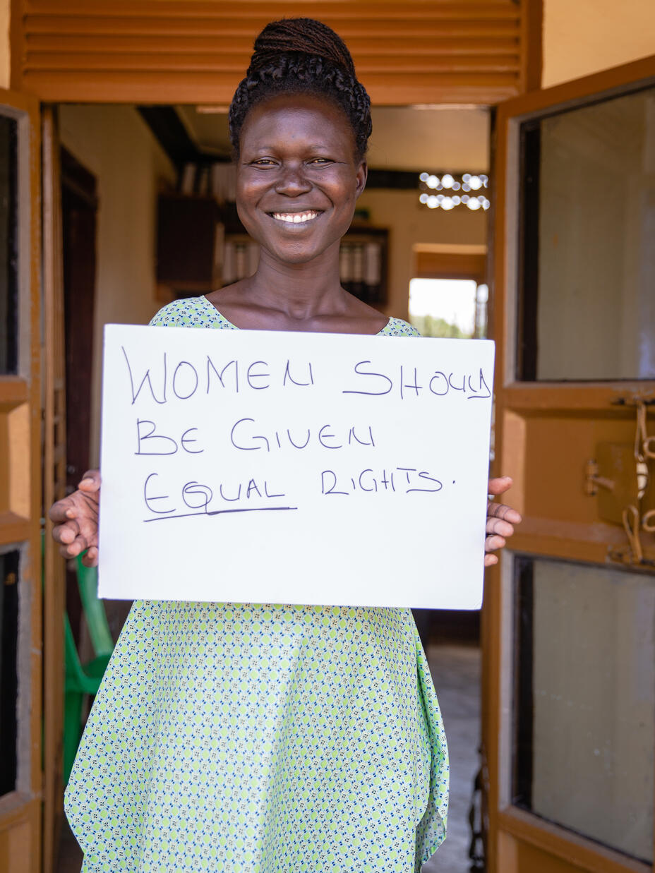 Grace Muuduru håller upp en skylt där det står att kvinnor ska ha lika rättigheter
