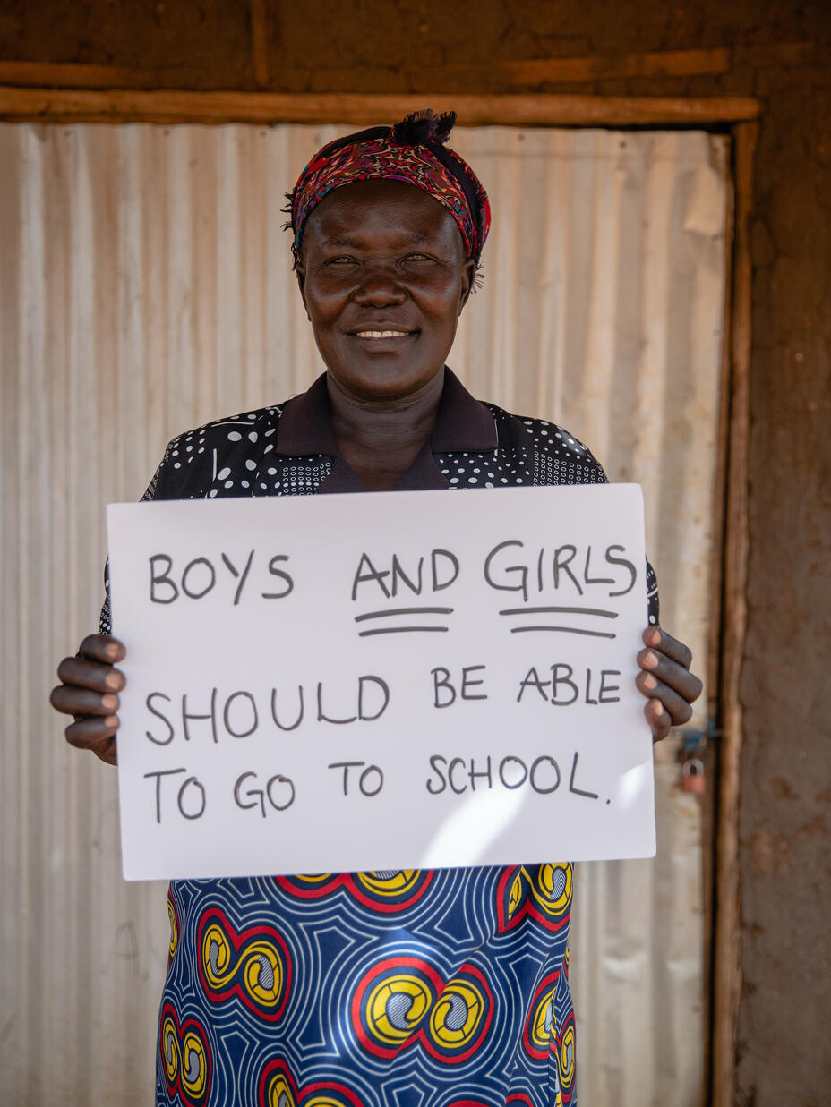 Jemimah grundaren av ’Togoleta’ håller upp en skylt som säger att både pojkar och flickor ska få gå i skolan.