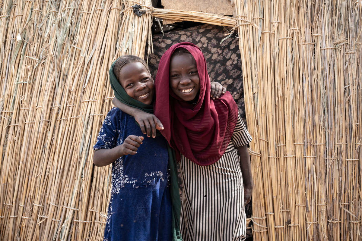 Två flickor i Chad håller om varandra och ler. 