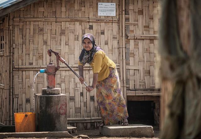 En kvinna pumpar vatten i Myanmar.