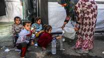 En kvinna i Gaza fyller på några barns vattenflaskor, det finns inte tillräckligt med rent vatten på plats.