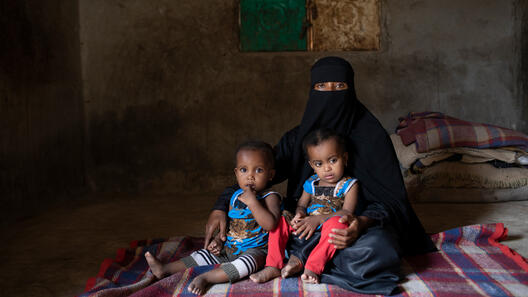 En mamma sitter med sina två barn i Jemen