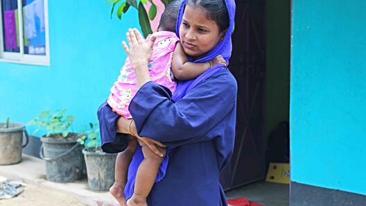 IRC-Hebamme Lovely Akter hält ihre Tochter im Arm