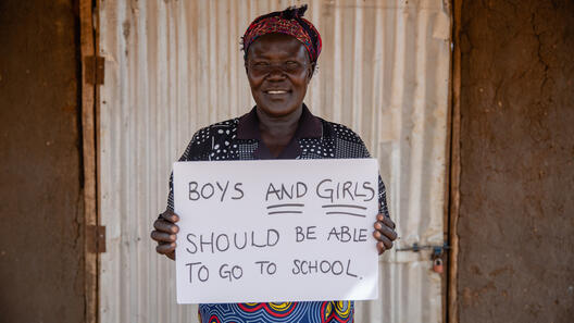 Jemimah håller en skylt där det står att både pojkar och flickor ska kunna få gå i skolan.