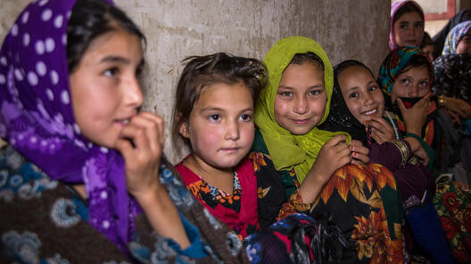 Flickor sitter mot en vägg i Afghanistan