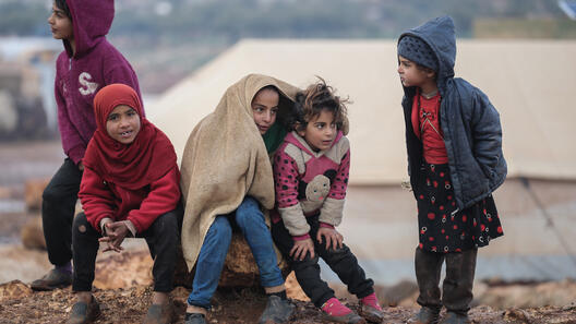 Syriska barn försöker hålla sig varma i ett läger för internflyktingar i Syrien.