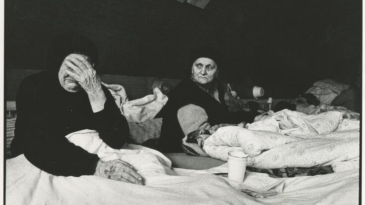 Två äldre kvinnor sitter i ett flyktingläger