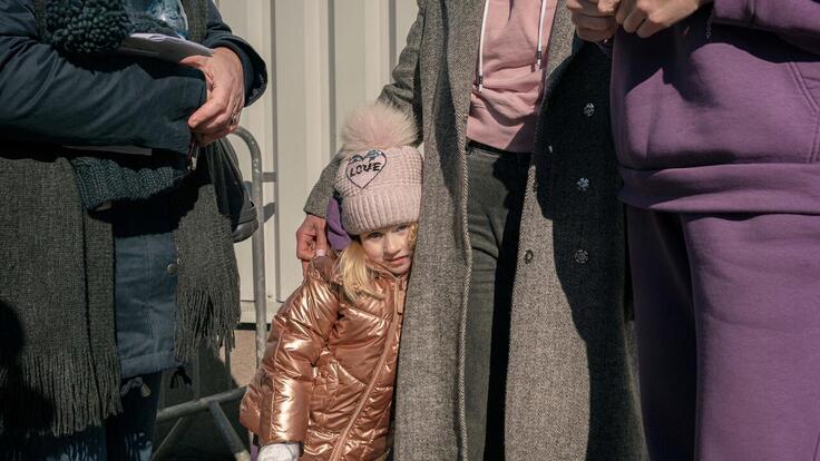 Ett barn gömmer sig bakom sin mamma efter att de flytt Ukraina